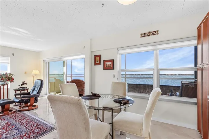 Dining space featuring light tile patterned floors, a textured ceiling, healthy amount of natural light, and a water view