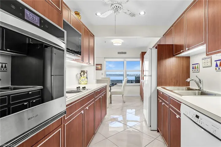 Kitchen with white appliances, light countertops, recessed lighting, wood finish cabinetry, and light tile patterned floors