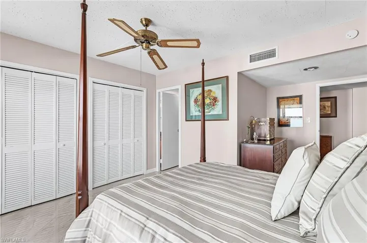 Bedroom with two closets, ceiling fan, and a textured ceiling