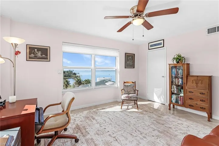 Home office featuring a water view, a ceiling fan, and light tile patterned floors