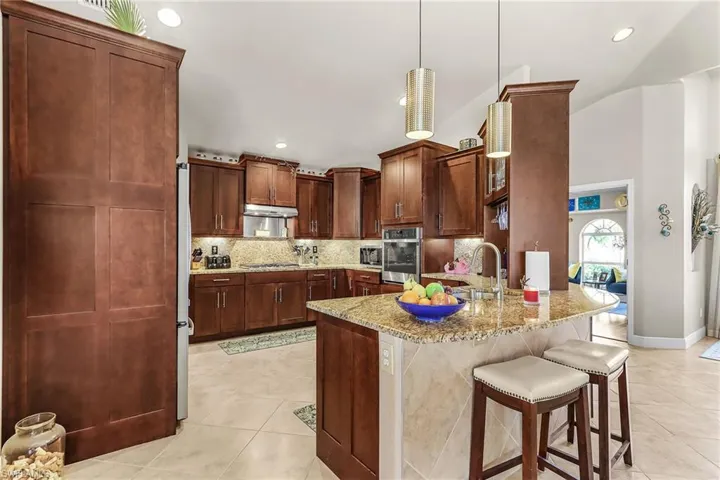 Kitchen with a kitchen breakfast bar, tasteful backsplash, a peninsula, light stone countertops, and stainless steel appliances