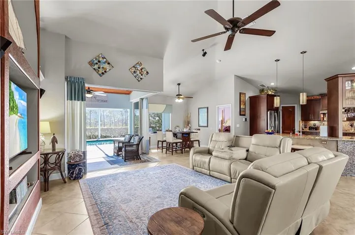 Living area featuring a ceiling fan, a sunroom, light tile patterned flooring, lofted ceiling, and recessed lighting