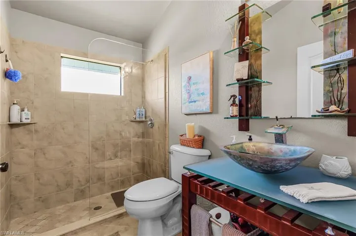 Bathroom with walk in shower, vanity, and a textured wall