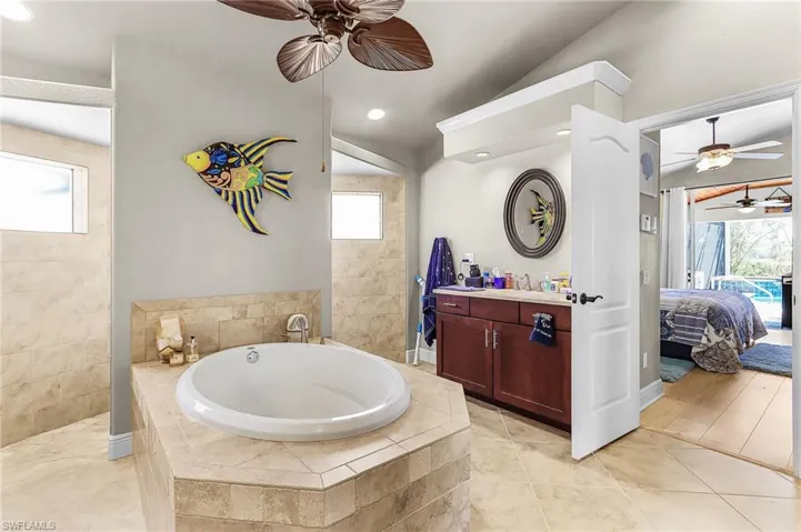 Ensuite bathroom featuring a ceiling fan, vanity, a bath, walk in shower, and light tile patterned floors