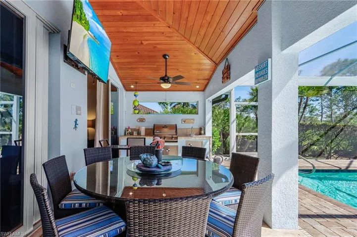 View of patio / terrace featuring an outdoor pool, a ceiling fan, an outdoor kitchen / dining area, a lanai, and a sunroom