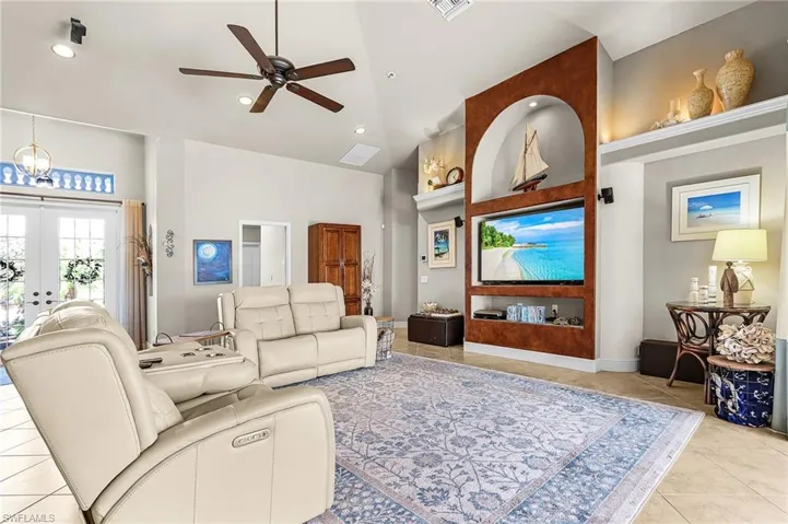 Living area with light tile patterned flooring, a ceiling fan, french doors, recessed lighting, and a high ceiling