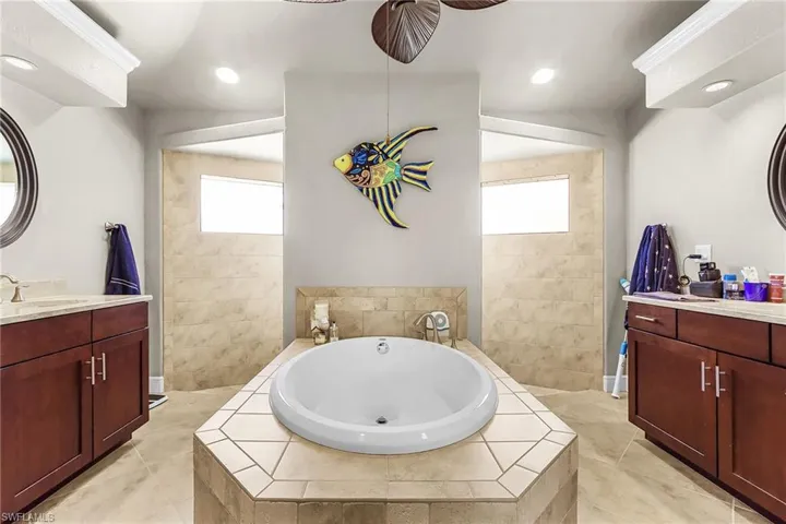 Full bath featuring two vanities, walk in shower, a bath, and recessed lighting