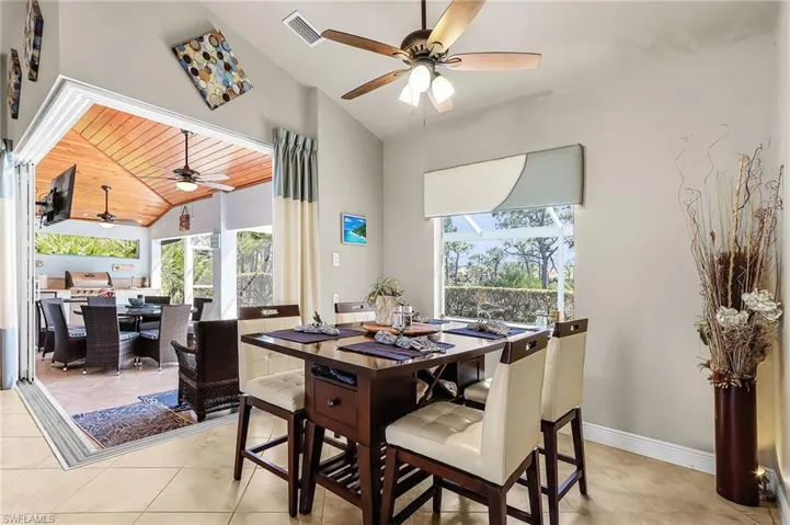 Dining room featuring a ceiling fan, lofted ceiling, and light tile patterned floors