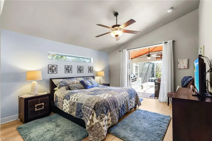 Bedroom with access to outside, light wood-style floors, vaulted ceiling, and a ceiling fan