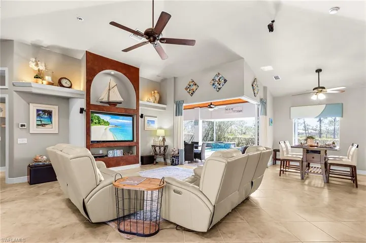 Living room with a ceiling fan, a sunroom, plenty of natural light, and a high ceiling