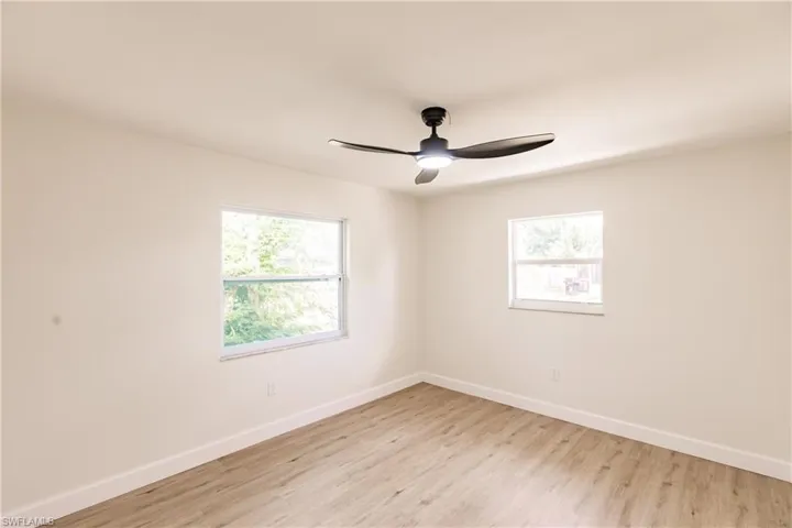 Empty room with light hardwood / wood-style floors, plenty of natural light, and ceiling fan