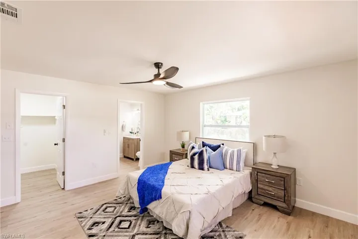 Bedroom featuring ceiling fan, light hardwood / wood-style floors, and ensuite bath