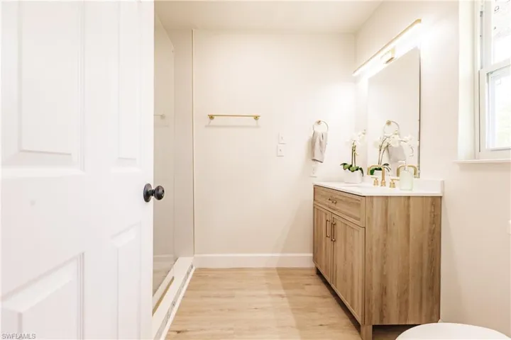 Bathroom featuring wood-type flooring, vanity, toilet, and a shower