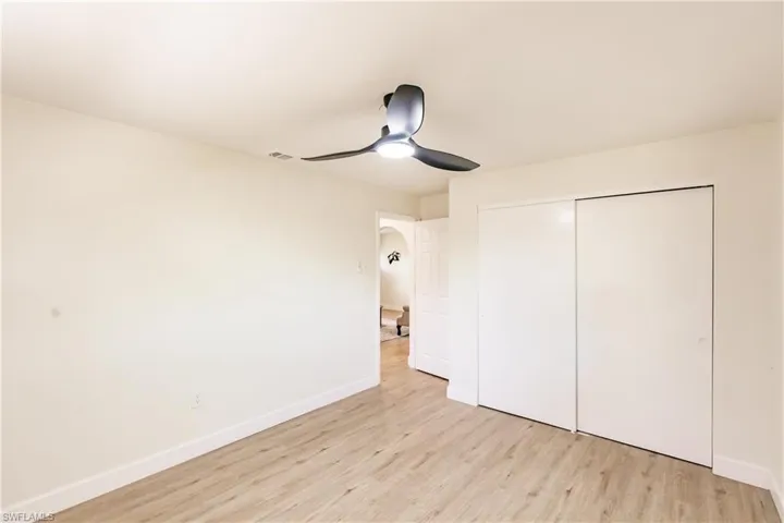 Unfurnished bedroom with ceiling fan, a closet, and light wood-type flooring