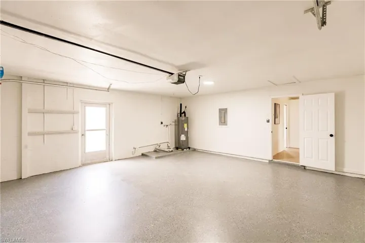 Garage featuring a garage door opener and electric water heater