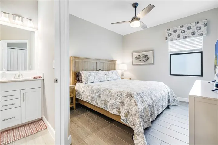 Bedroom with light wood-type flooring, a sink, baseboards, and ceiling fan