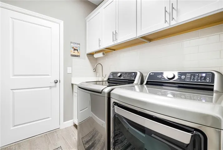 Laundry room with light wood finished floors, washing machine and clothes dryer, and cabinet space