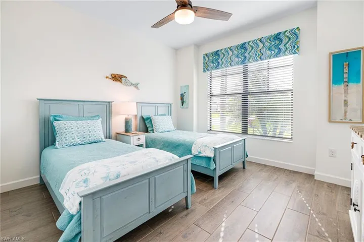 Bedroom with ceiling fan, light wood finished floors, and baseboards