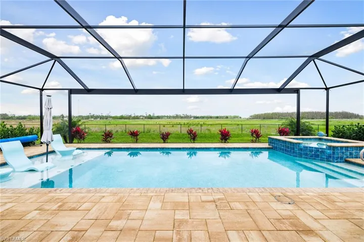 View of swimming pool featuring a patio, glass enclosure, fence, and a pool with connected hot tub