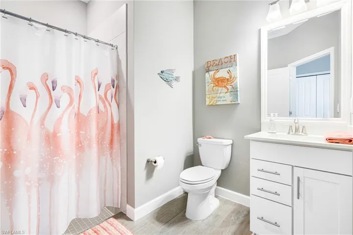 Bathroom with toilet, a shower with shower curtain, wood finished floors, vanity, and baseboards