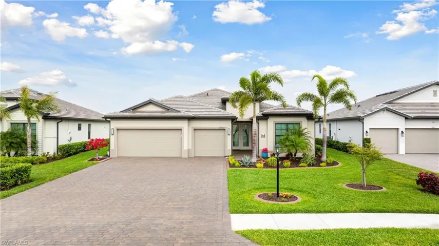 View of front of property with a garage, decorative driveway, a front lawn, and stucco siding