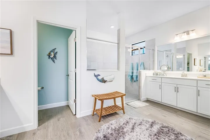Full bathroom with wood finished floors, a shower stall, vanity, and baseboards