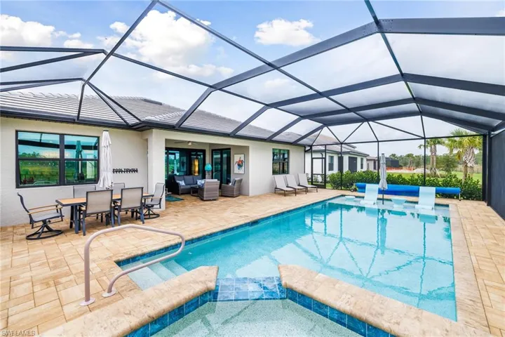 View of swimming pool featuring glass enclosure, a pool with connected hot tub, a patio area, and an outdoor living space