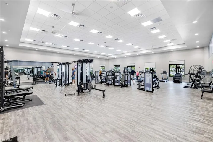 Gym with visible vents, a tray ceiling, wood finished floors, and a towering ceiling