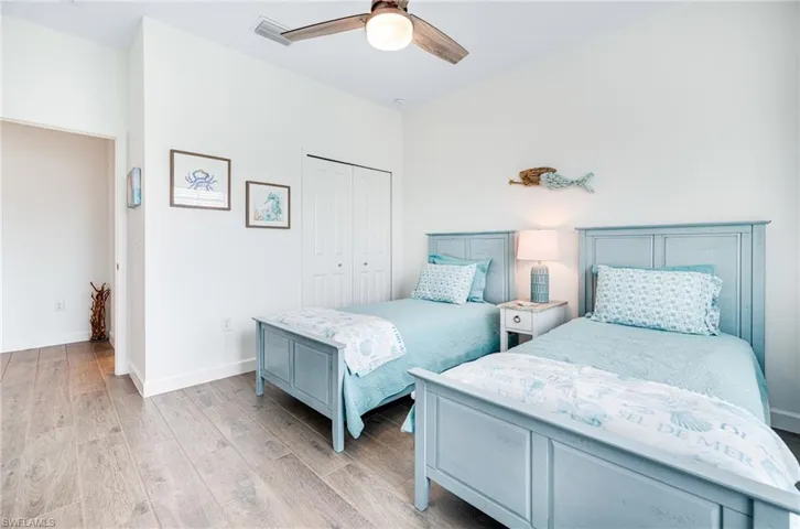 Bedroom with visible vents, baseboards, a ceiling fan, light wood-style floors, and a closet