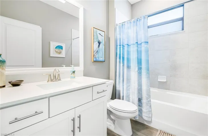 Full bathroom featuring toilet, shower / bathtub combination with curtain, wood finished floors, and vanity