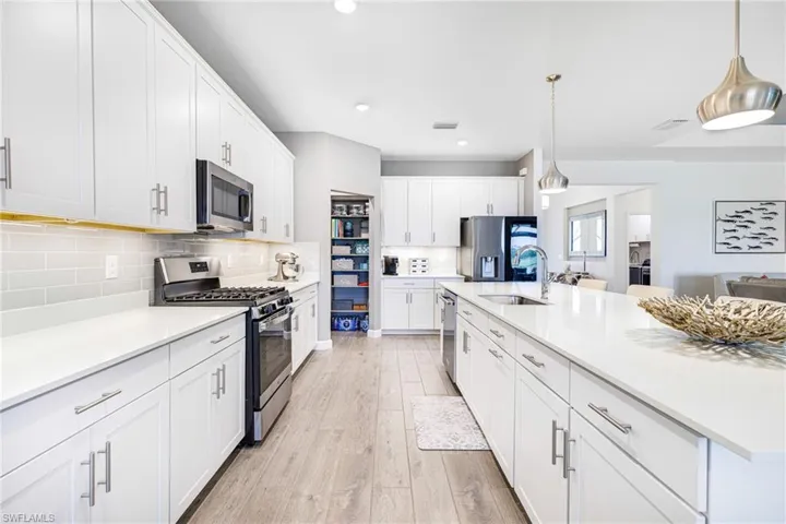 Kitchen with light wood-style flooring, appliances with stainless steel finishes, light countertops, and a sink