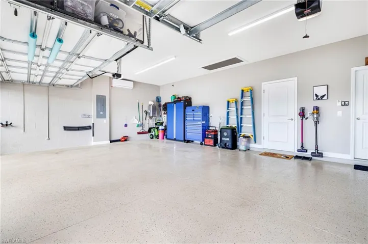 Garage featuring concrete block wall, electric panel, and a garage door opener