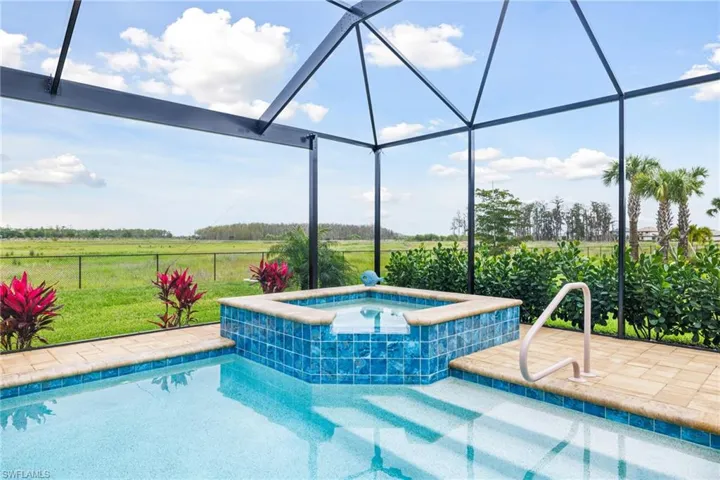 View of pool with a patio, glass enclosure, a rural view, an in ground hot tub, and fence