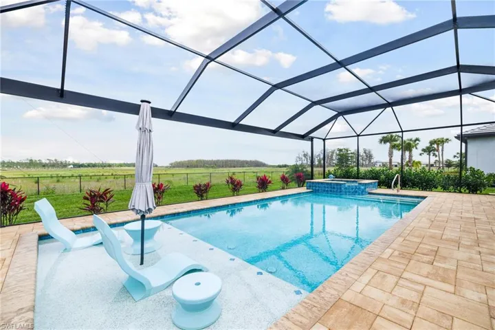 View of pool featuring a rural view, a lanai, fence, a pool with connected hot tub, and a patio area