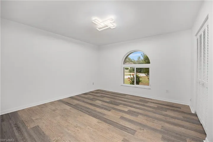 Unfurnished bedroom featuring dark wood-style flooring and a closet