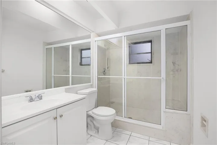 Full bath with vanity, a marble finish shower, and light marble finish floors