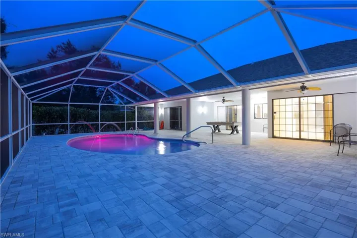 Swimming pool with a sunroom, glass enclosure, and a patio