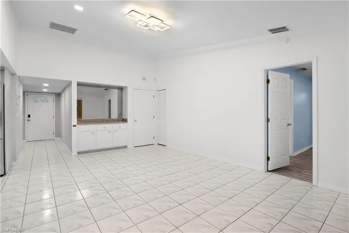 Unfurnished living room featuring a towering ceiling and recessed lighting