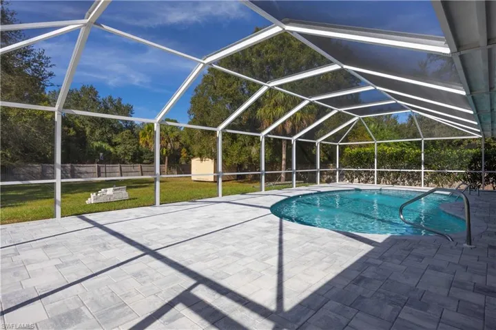 Swimming pool with glass enclosure, a sunroom, a fenced backyard, and a patio