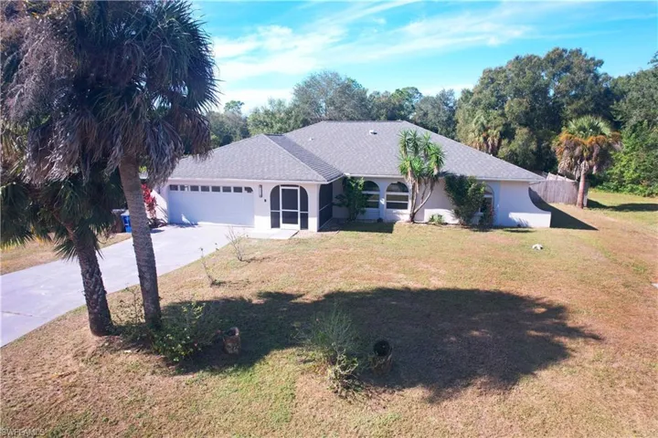 Single story home featuring driveway, stucco siding, a front yard, an attached garage, and a shingled roof