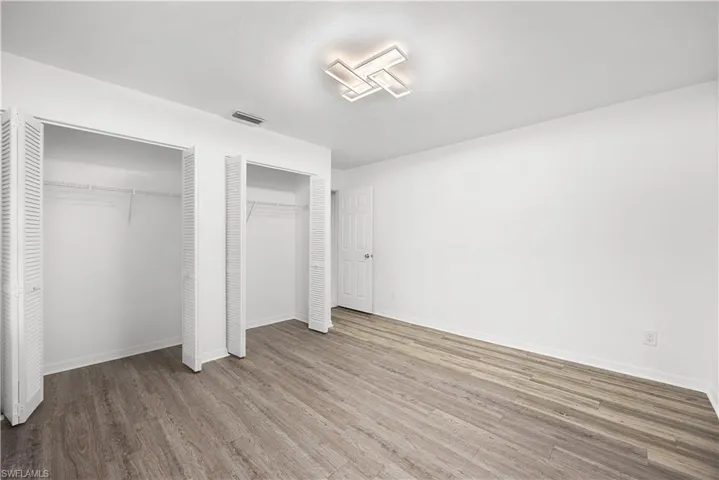 Unfurnished bedroom with multiple closets and wood finished floors