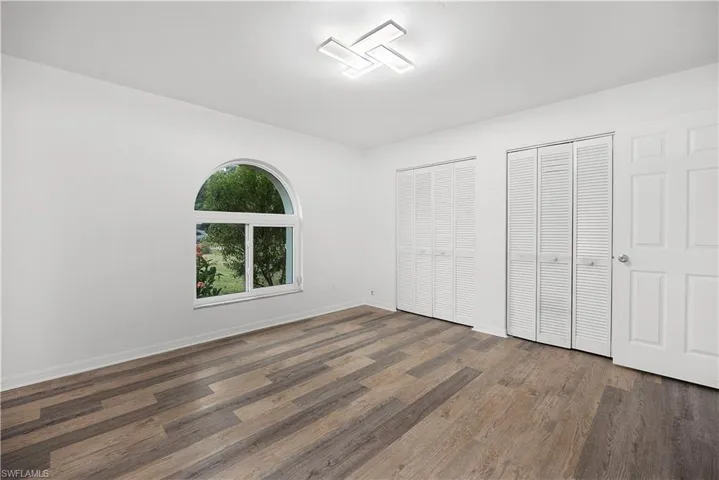 Unfurnished bedroom with two closets and dark wood finished floors