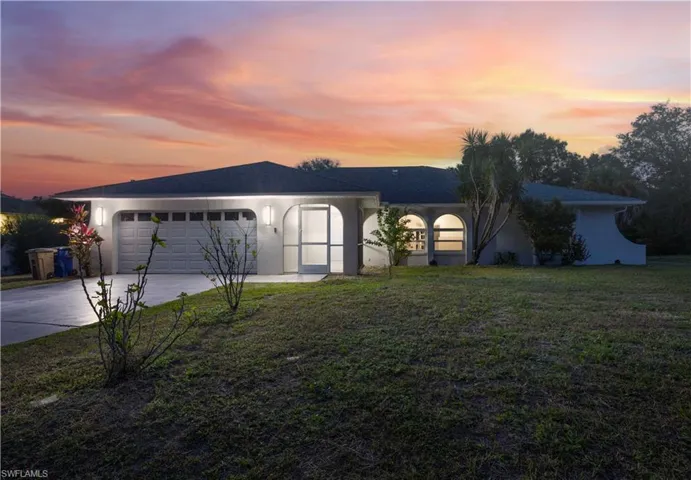 Ranch-style home with a lawn, driveway, stucco siding, and an attached garage