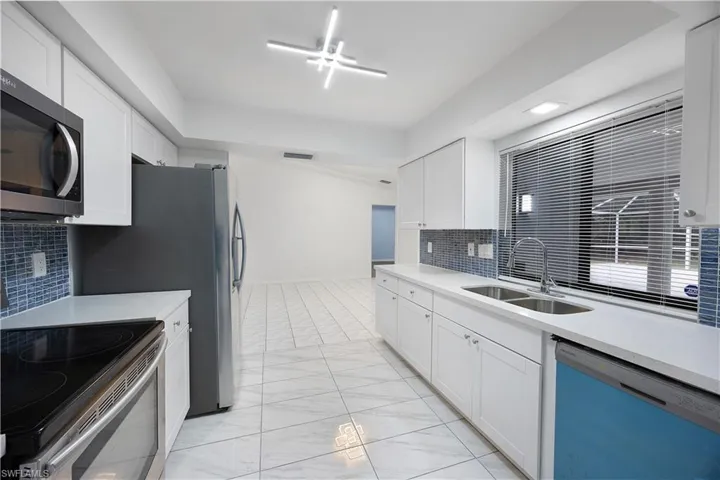 Kitchen with stainless steel appliances, decorative backsplash, and white cabinetry