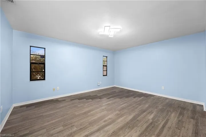 Spare room featuring dark wood-style floors and baseboards