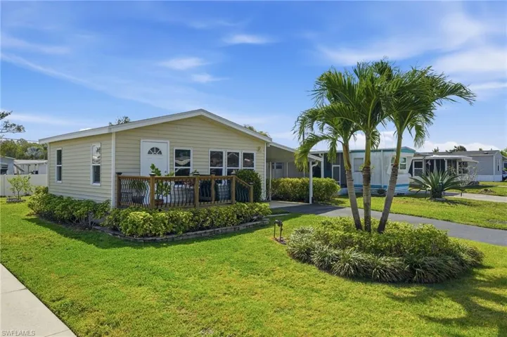 FRONT VIEW OF HOME SHOWING FRONT DECK, NICELY LANDSCAPED YARD, AND EXTRA-LONG PAVED DRIVE..