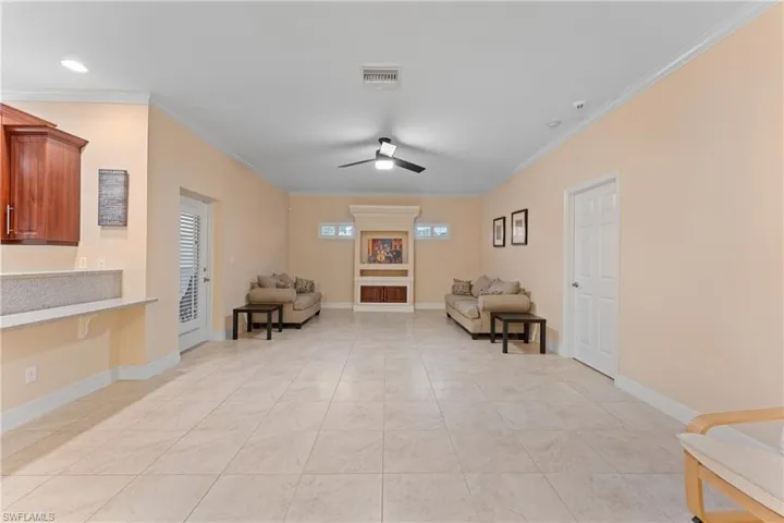Living area featuring ceiling fan, light tile patterned flooring, and crown molding