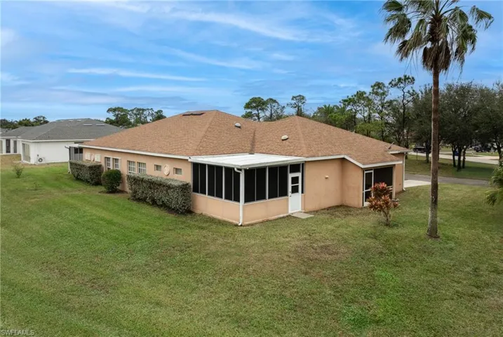 Rear view of house featuring a sunroom and a lawn
