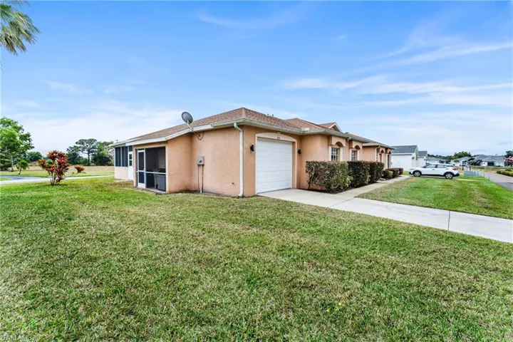 View of side of property featuring a garage, a yard, and a sunroom