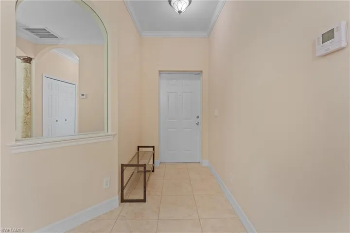 Hallway featuring light tile patterned floors and ornamental molding
